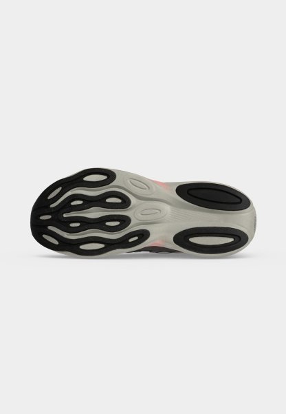 Suela de una zapatilla de correr con patrones antideslizantes de goma en blanco y negro sobre un fondo gris claro.