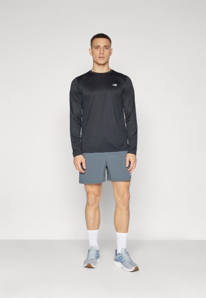 Conjunto deportivo para hombre que incluye una camiseta negra de manga larga y pantalones cortos grises. Zapatillas grises con detalles azules, calcetines blancos y un diseño simple.