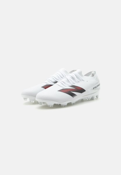 Botas de fútbol blancas con logo rojo y negro, parte superior texturizada y tacos moldeados para jugar en terreno firme, mostradas desde una vista lateral en ángulo.