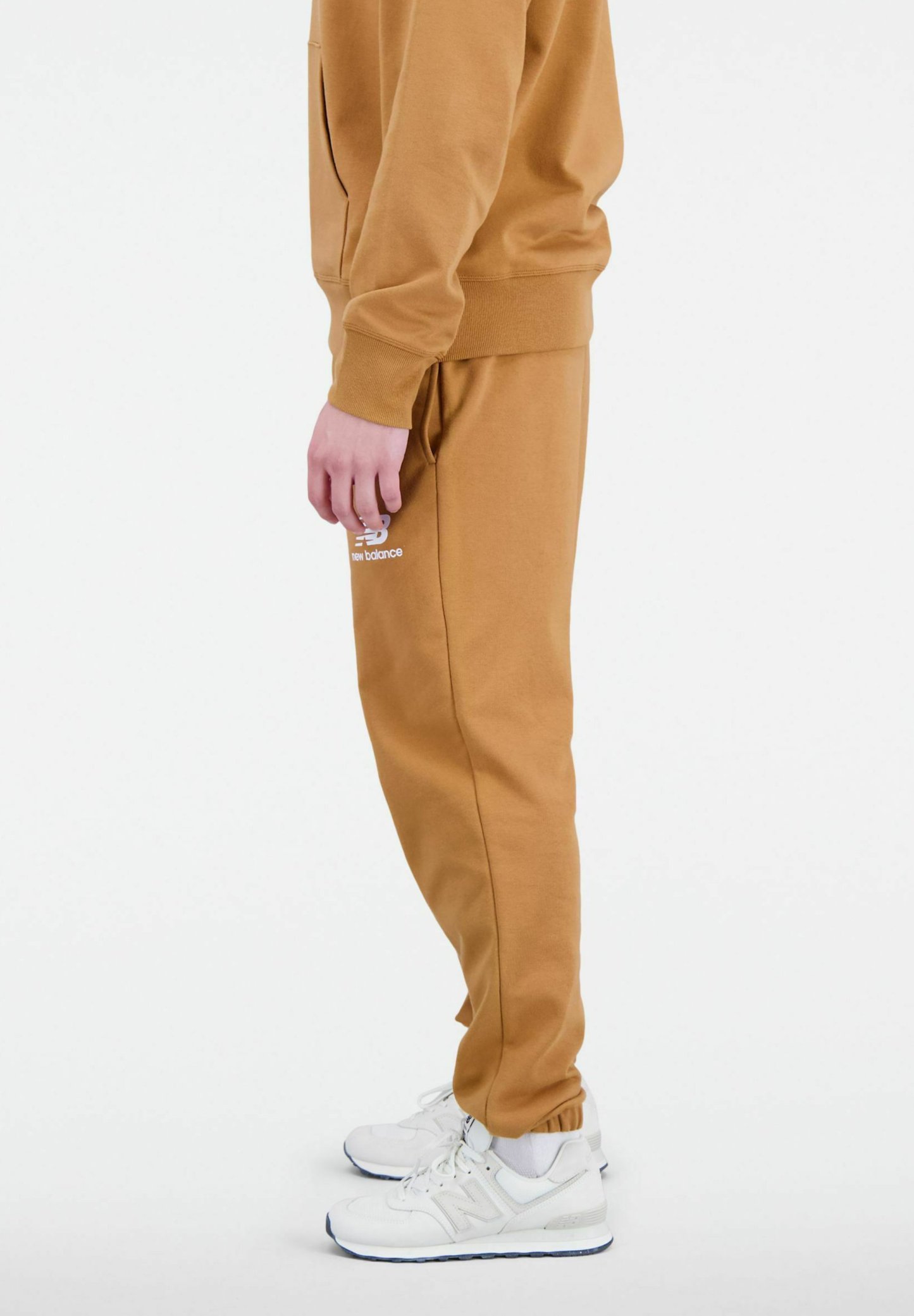 Pantalones jogger de algodón marrón con cintura ajustable, bolsillos laterales y detalle de logo en blanco. Combinados con zapatillas blancas con acentos grises.