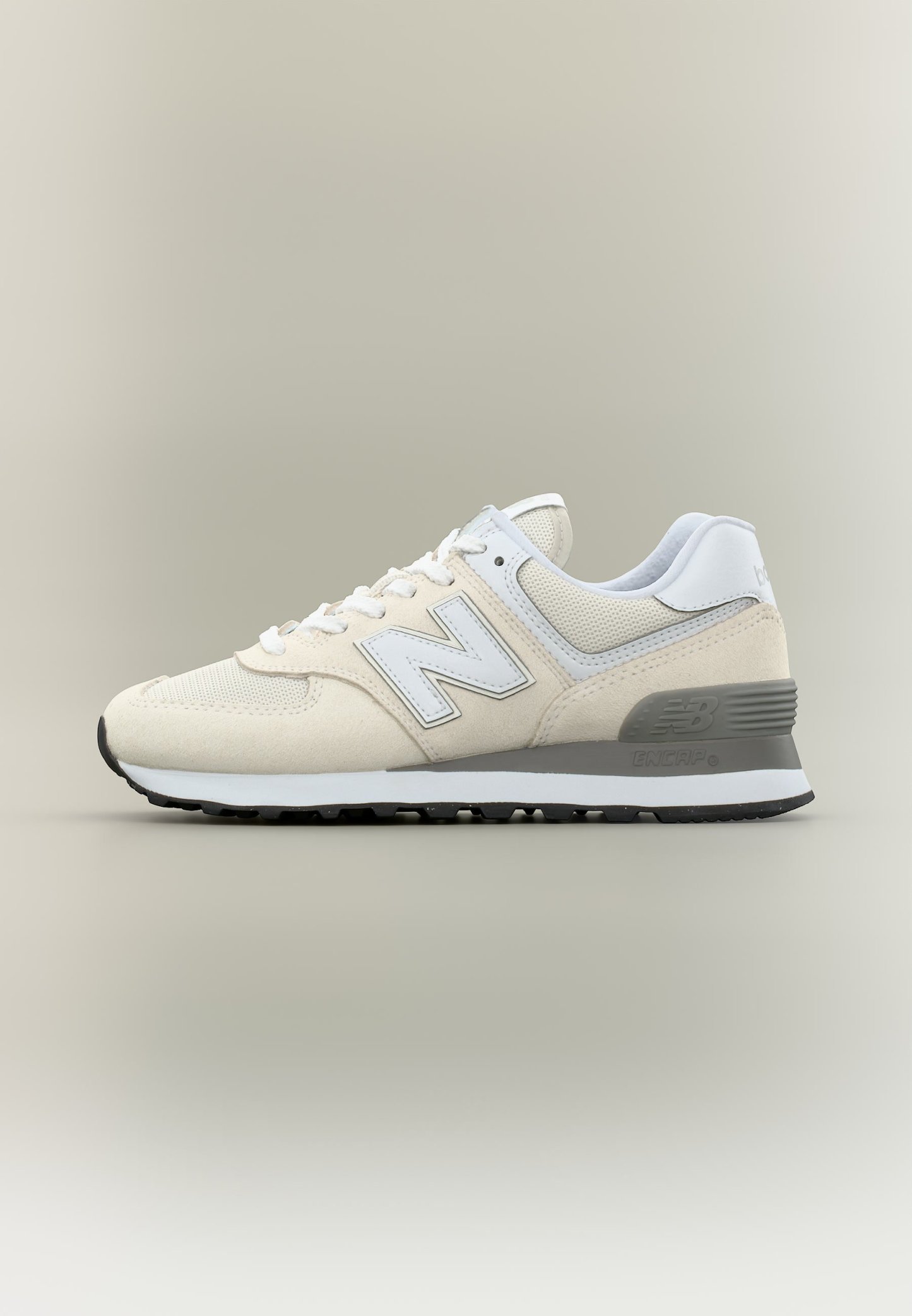 Zapatilla New Balance beige y blanca con parte superior de malla y ante, diseño con cordones y suela acolchada gris sobre fondo beige.