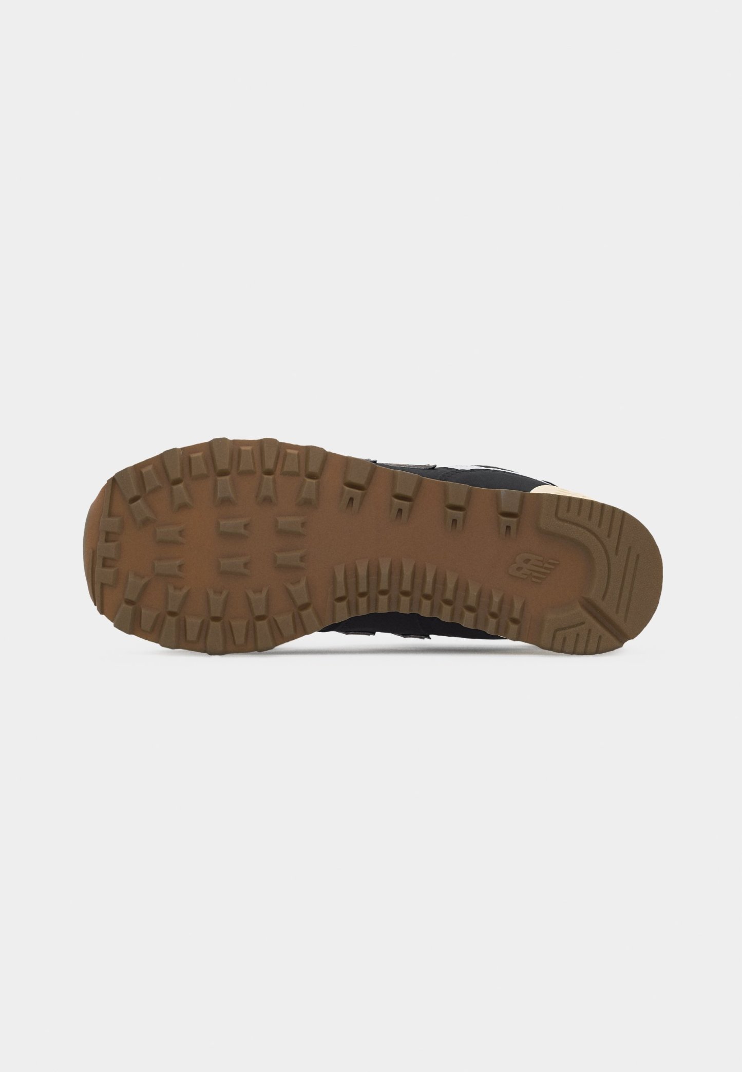Suela de zapatilla negra con patrón de tracción en marrón oscuro y logo de New Balance en el talón, vista desde abajo sobre un fondo blanco.