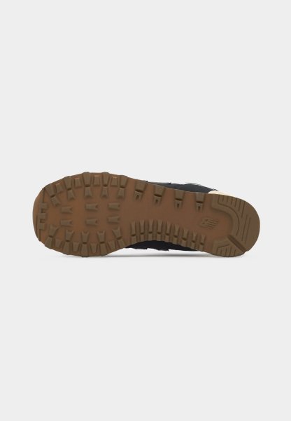Suela de zapatilla negra con patrón de tracción en marrón oscuro y logo de New Balance en el talón, vista desde abajo sobre un fondo blanco.