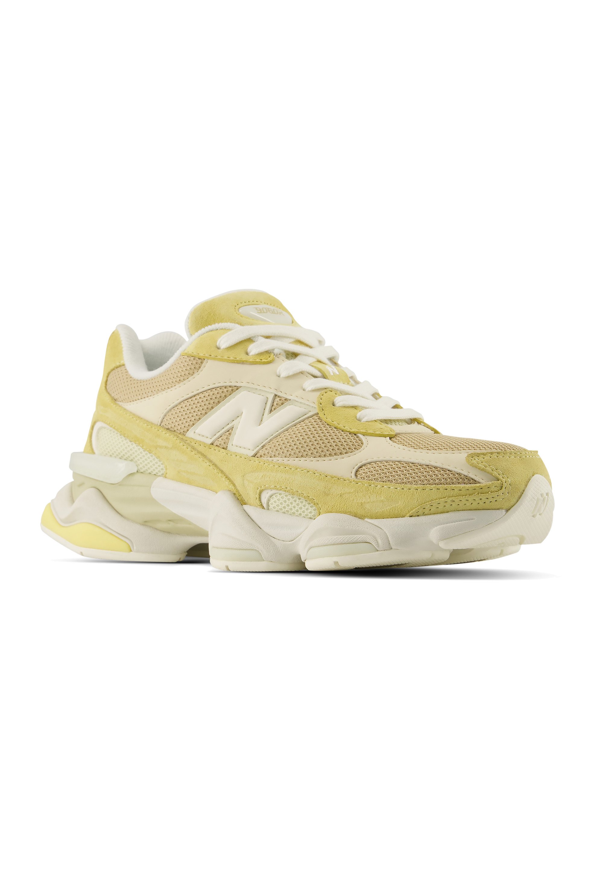 Zapatilla deportiva beige y amarillo claro con cordones blancos, paneles de malla y ante, suela gruesa y un logo "N" destacado en el lateral.