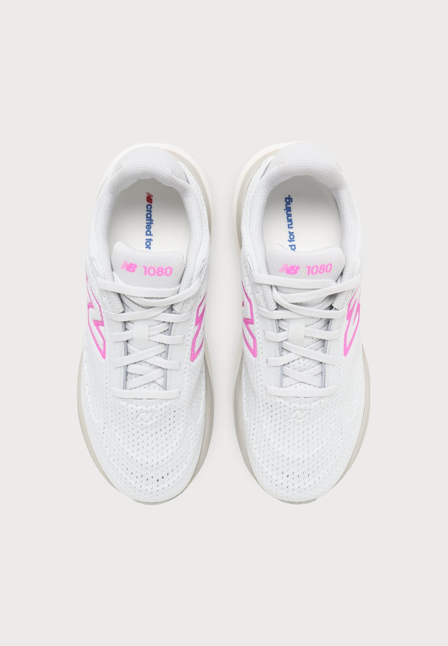 Par de zapatillas de correr New Balance 1080 blancas con logo y cordones rosas, vistas desde arriba sobre un fondo claro.