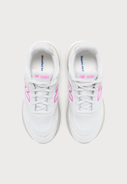 Par de zapatillas de correr New Balance 1080 blancas con logo y cordones rosas, vistas desde arriba sobre un fondo claro.