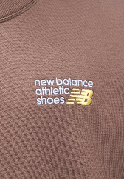 Textil marrón con la inscripción "new balance athletic shoes" bordada en blanco con un acento amarillo en un escote redondeado.