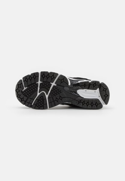 Suela de zapatilla atlética negra con un patrón texturizado, que presenta treads hexagonales para agarre y acentos grises alrededor de los laterales.
