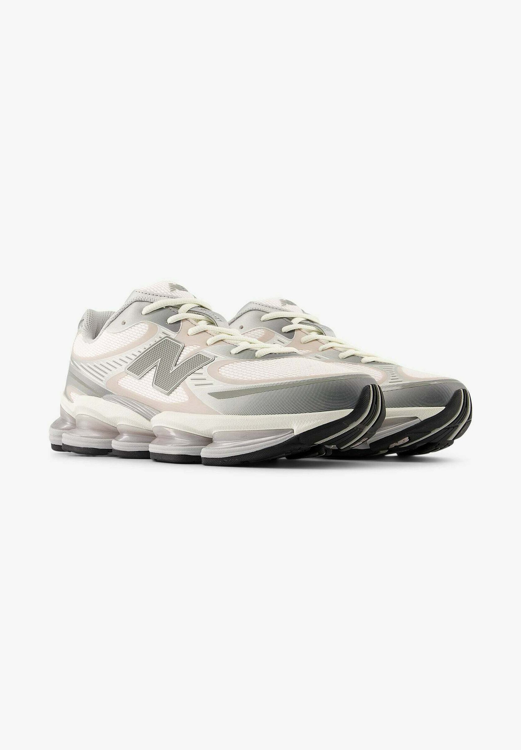 Par de zapatillas deportivas en gris claro y blanco con suelas acolchadas y segmentadas, y el logo "N" en los laterales, mostradas desde una vista frontal en tres cuartos.