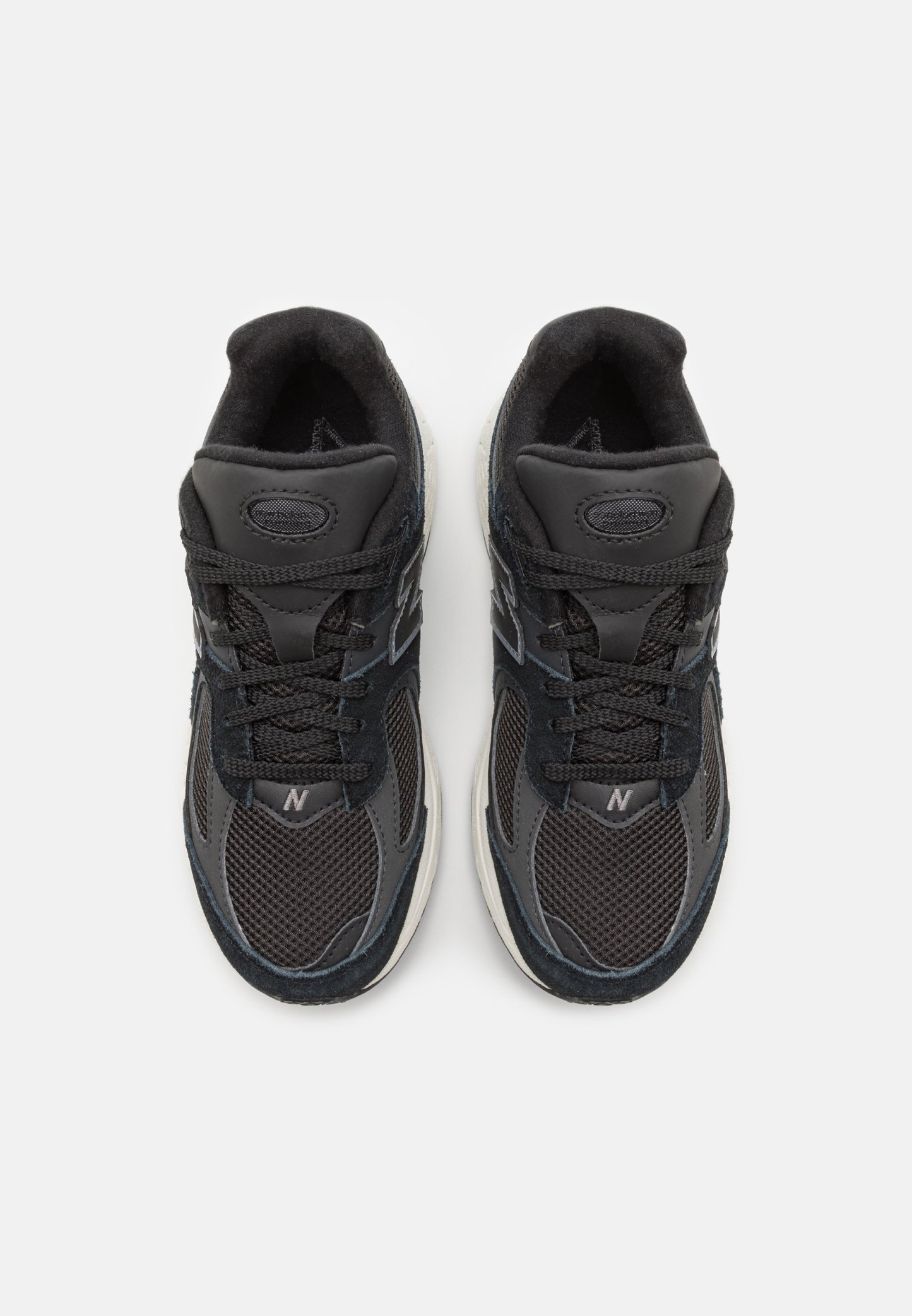 Zapatillas deportivas negras con materiales de malla y gamuza, que cuentan con un collar acolchado, cierre con cordones y una suela de goma blanca.