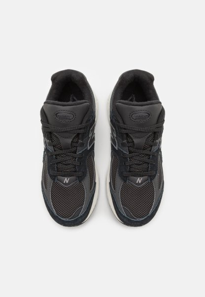 Zapatillas deportivas negras con materiales de malla y gamuza, que cuentan con un collar acolchado, cierre con cordones y una suela de goma blanca.