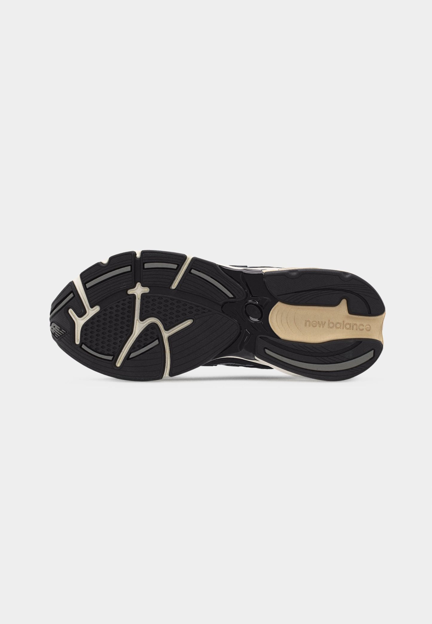 Suela de zapatilla New Balance en negro y beige que muestra patrones texturizados de agarre y el nombre de la marca en la sección del talón.