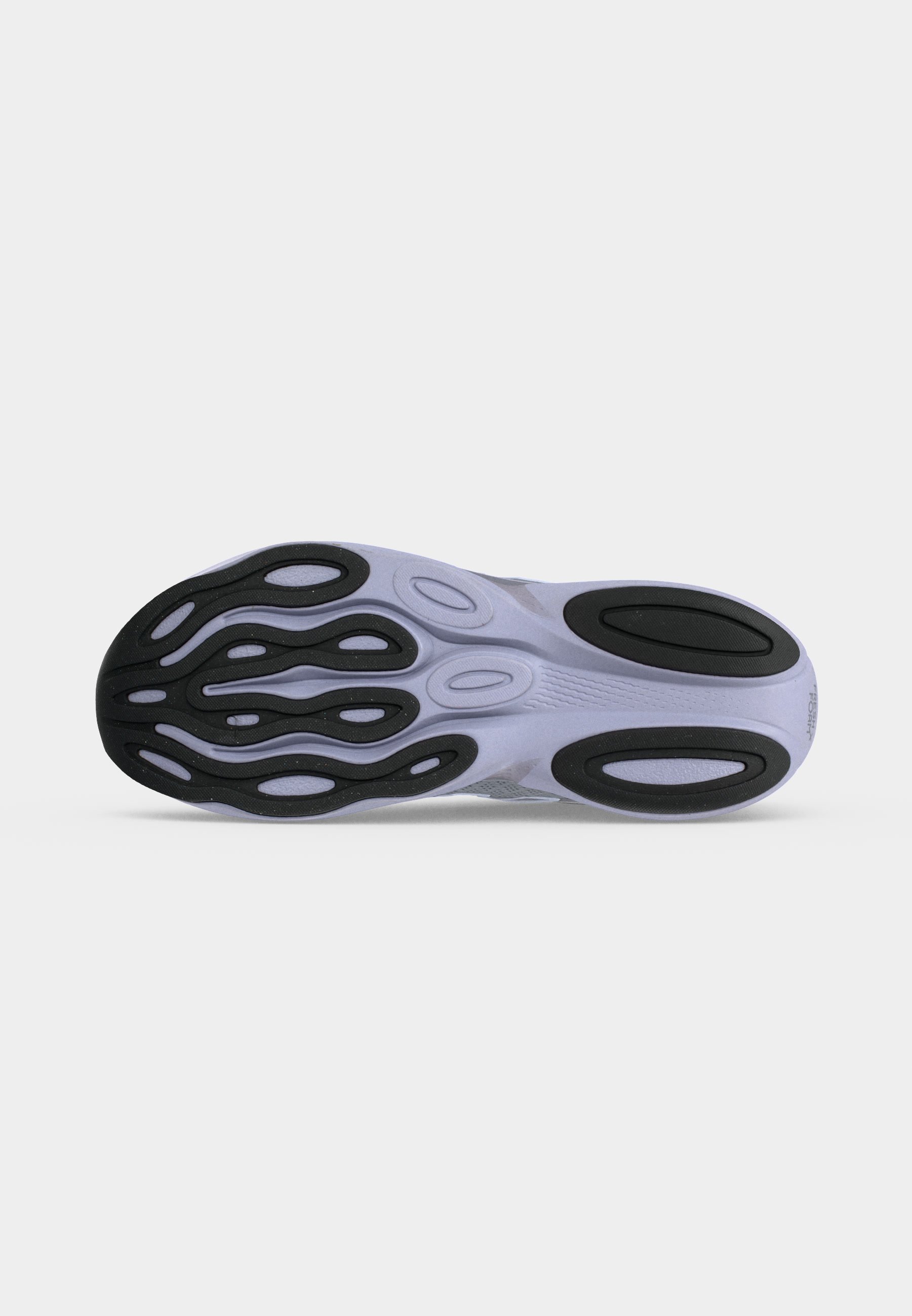 Suela de un zapato deportivo con almohadillas de tracción de goma negra en una suela exterior de color claro, diseñada para agarre y flexibilidad.