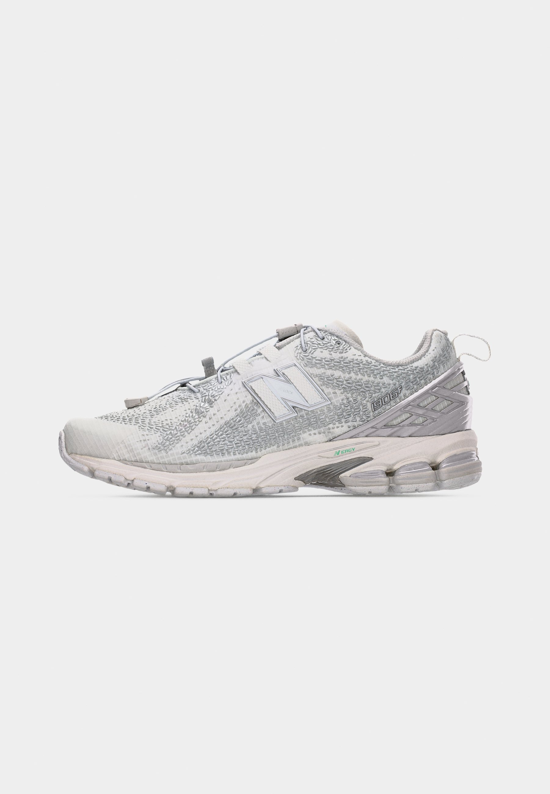 Zapatilla New Balance 1906R blanca y gris con parte superior texturizada, suela acolchada, detalles reflectantes y tira para tirar en el talón.
