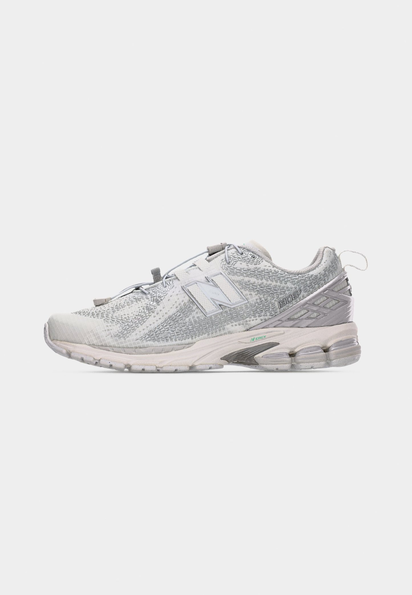 Zapatilla New Balance 1906R blanca y gris con parte superior texturizada, suela acolchada, detalles reflectantes y tira para tirar en el talón.