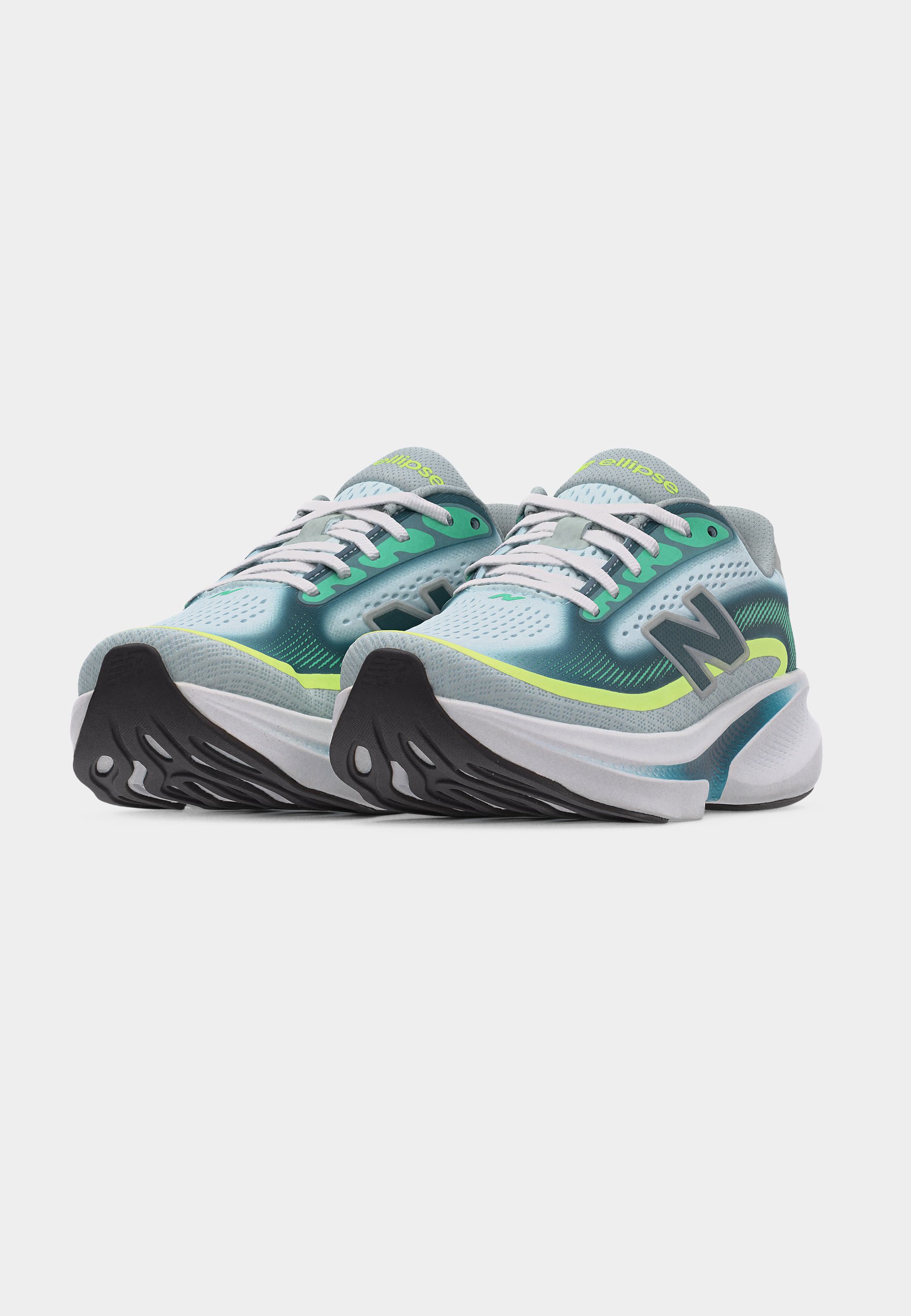 Par de zapatillas para correr en tonos azul verdoso, verde y gris con cordones blancos, suelas negras y logo "N" en los laterales, mostradas desde un ángulo frontal sobre un fondo blanco.