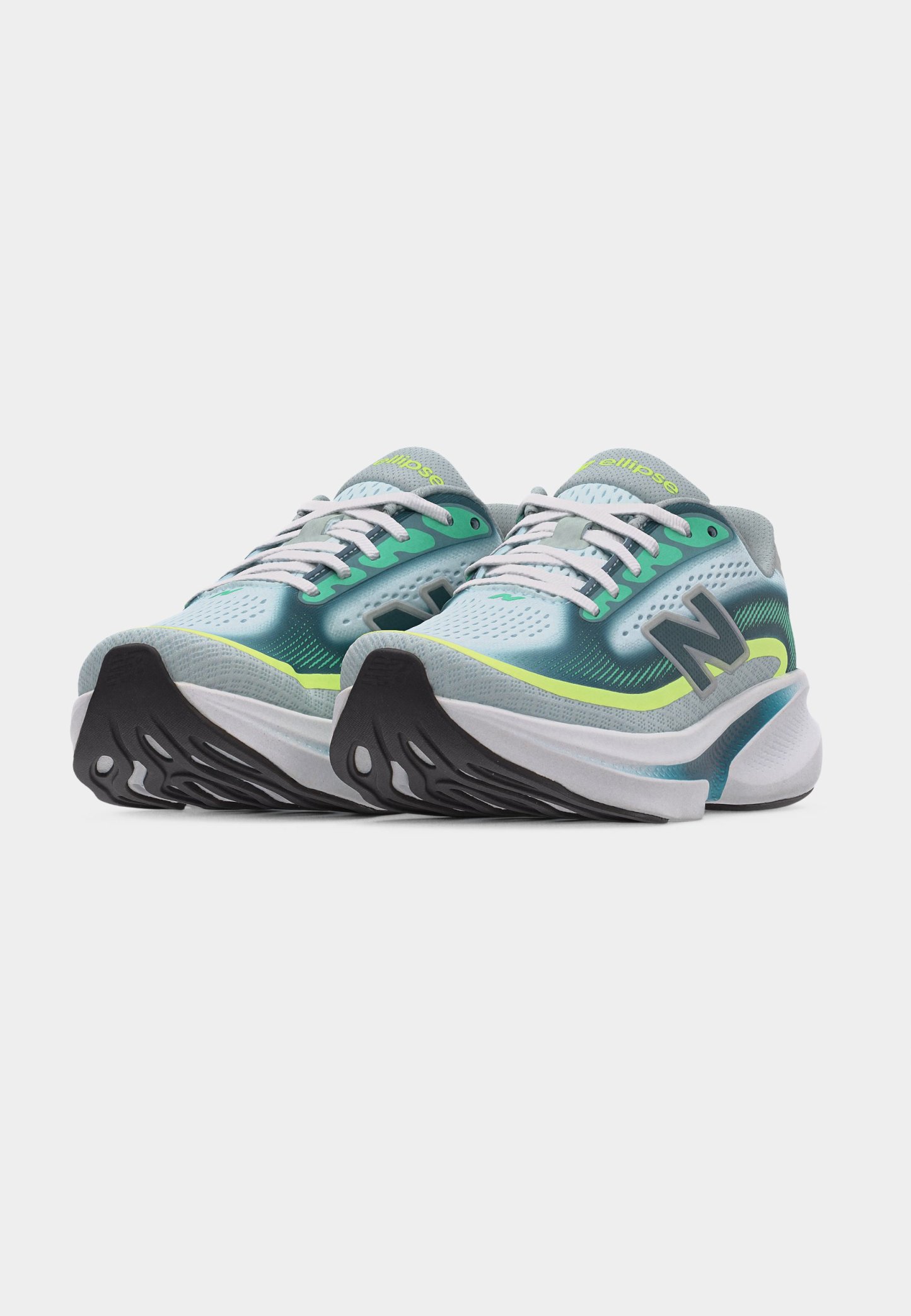 Par de zapatillas para correr en tonos azul verdoso, verde y gris con cordones blancos, suelas negras y logo "N" en los laterales, mostradas desde un ángulo frontal sobre un fondo blanco.