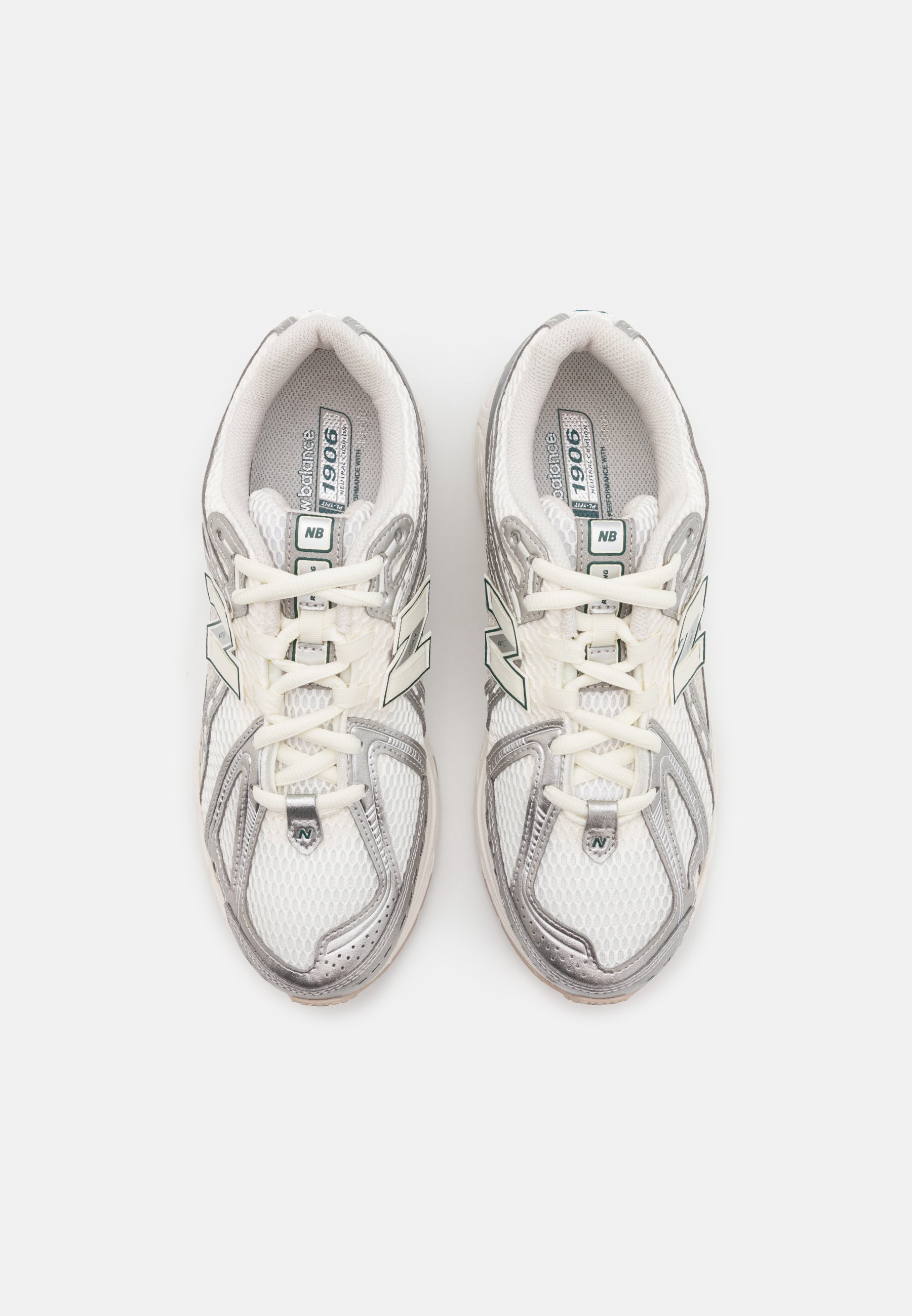 Zapatillas deportivas blancas de malla con detalles en plata. Las características incluyen cordones, una marca en la lengüeta y una suela acolchada. La parte superior tiene un diseño texturizado.