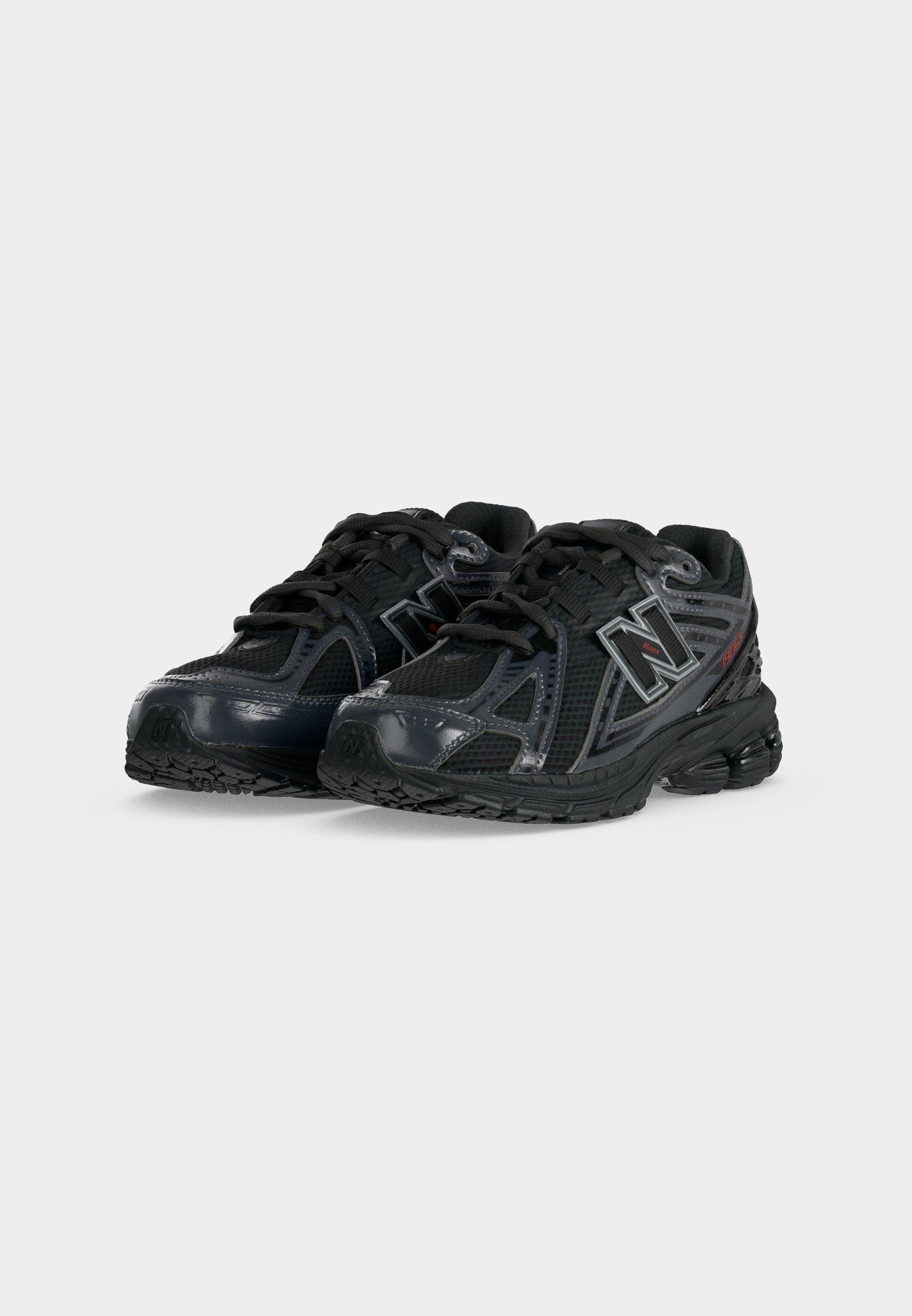Par de zapatillas negras de running deportivas con paneles de malla y sintéticos, diseño con cordones y logo de New Balance en los lados, mostradas sobre fondo blanco.