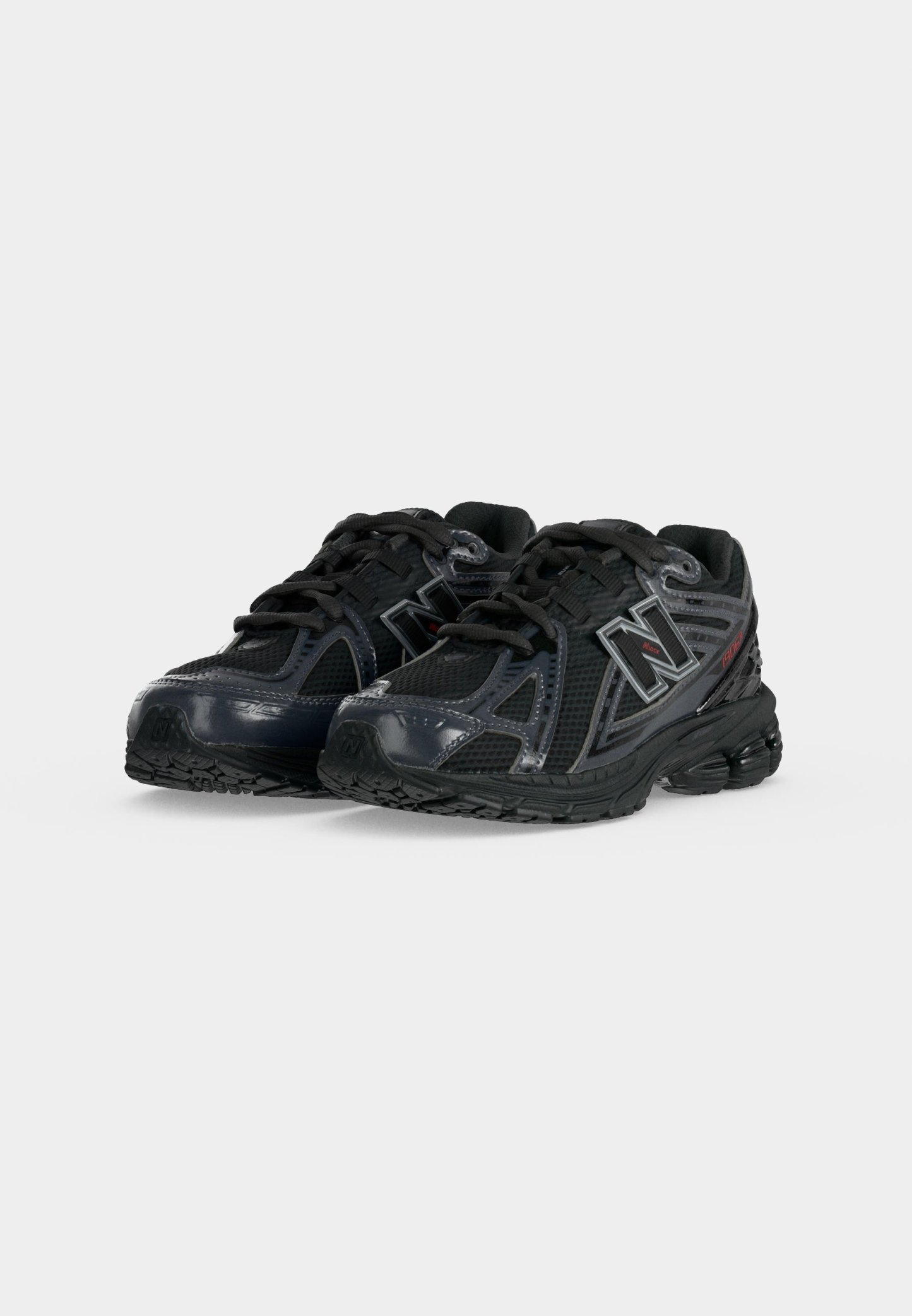 Par de zapatillas negras de running deportivas con paneles de malla y sintéticos, diseño con cordones y logo de New Balance en los lados, mostradas sobre fondo blanco.