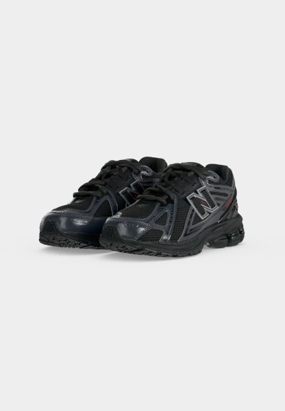 Par de zapatillas negras de running deportivas con paneles de malla y sintéticos, diseño con cordones y logo de New Balance en los lados, mostradas sobre fondo blanco.