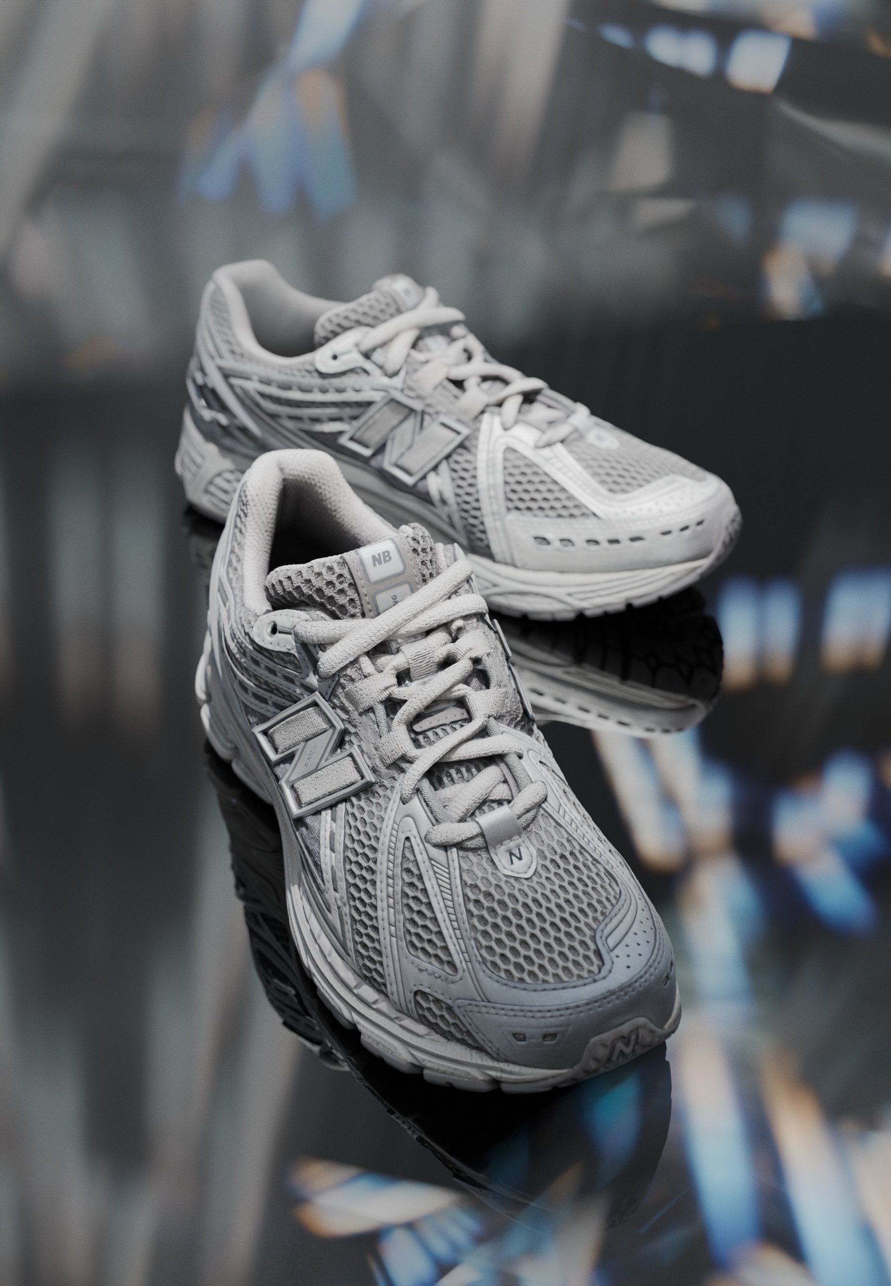 Zapatillas deportivas grises que presentan materiales de malla y sintéticos, puntera redondeada, suela acolchada, sistema de cordones y un destacado logo "N" en el costado.