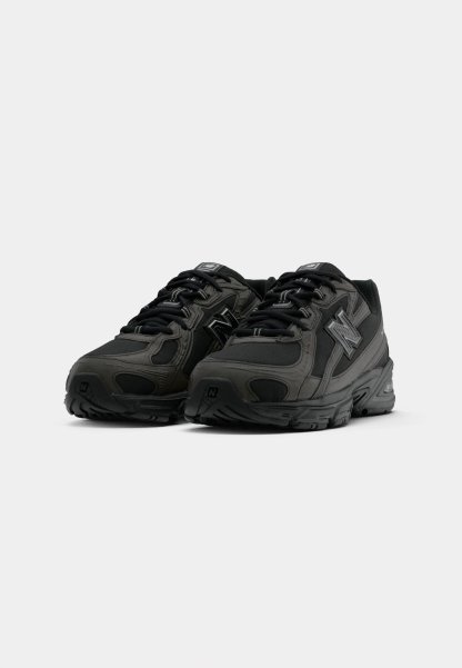 Par de zapatillas deportivas de New Balance en negro y gris oscuro con cordones, parte superior de malla y sintético, vista frontal en ángulo sobre fondo blanco.