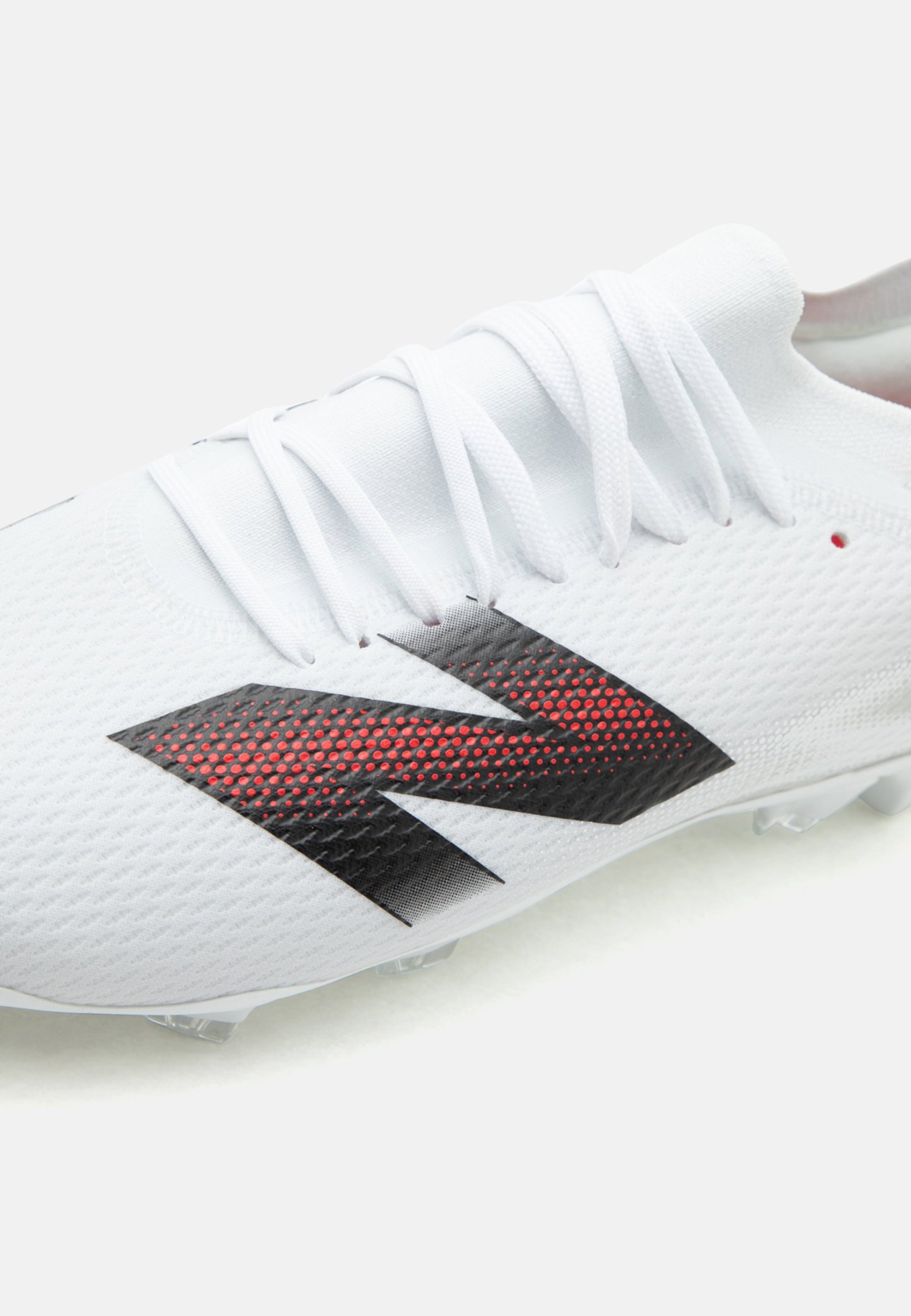 Bota de fútbol blanca con cordones blancos y un gran logo "N" negro y rojo con puntos en el lateral.