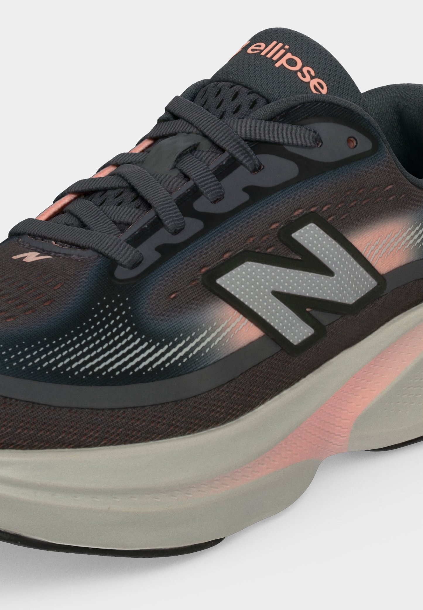 Primer plano de zapatilla de running New Balance negra y rosa con suela gris y logo "N" en el lateral, mostrando cordones y detalles de la parte superior de malla.