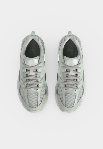 Par de zapatillas deportivas de color gris claro y verde menta con detalles de malla y cuero, vistas desde arriba sobre un fondo blanco.