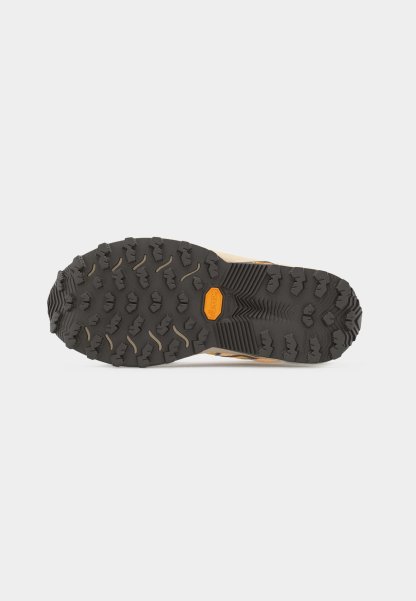 Suela Vibram negra y resistente de una bota de senderismo beige con patrones de banda de rodadura profunda para un mejor agarre sobre un fondo blanco.