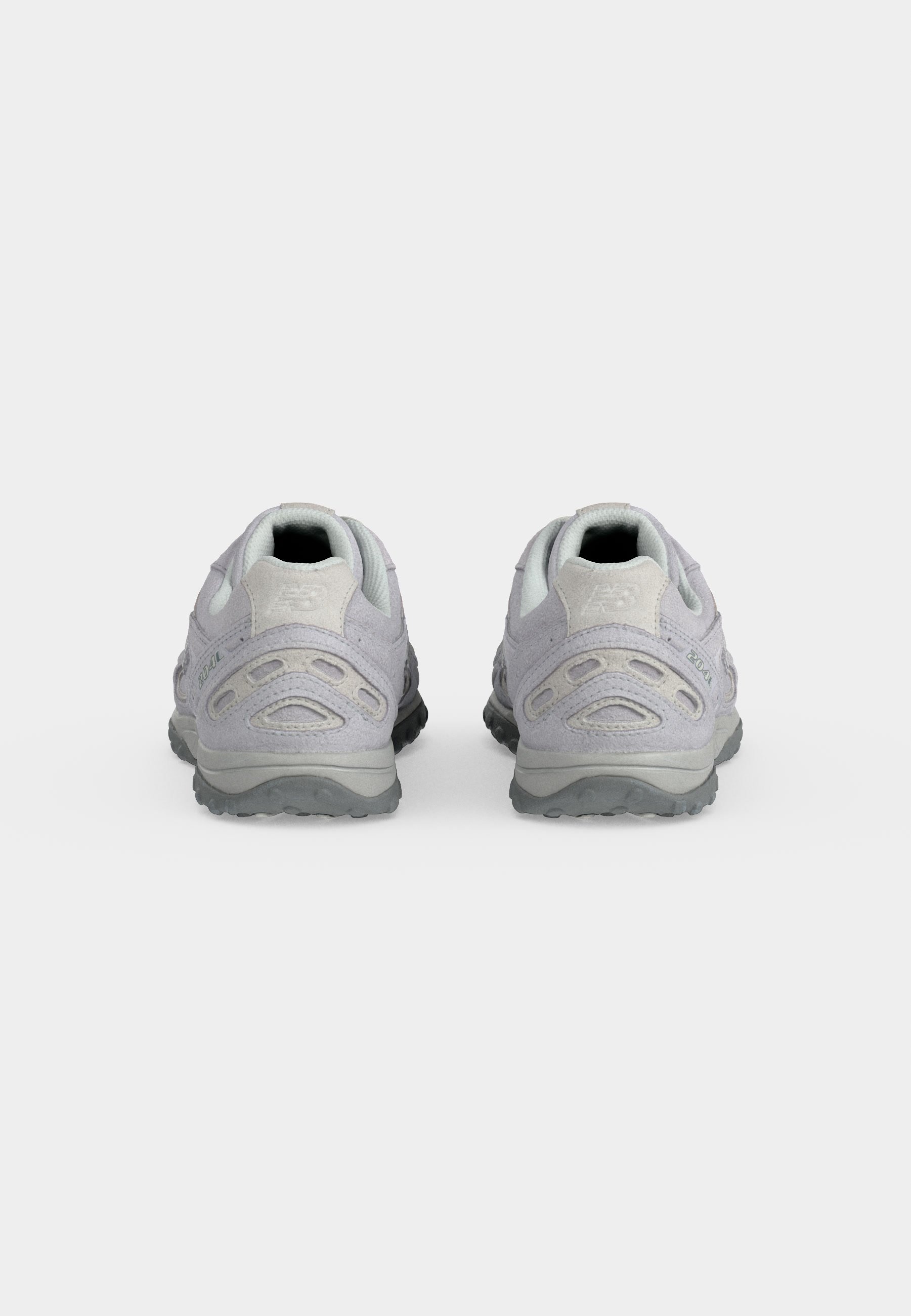 Par de zapatillas deportivas de color gris claro vistas desde los talones, con suelas texturizadas y detalles en ante sobre un fondo blanco.