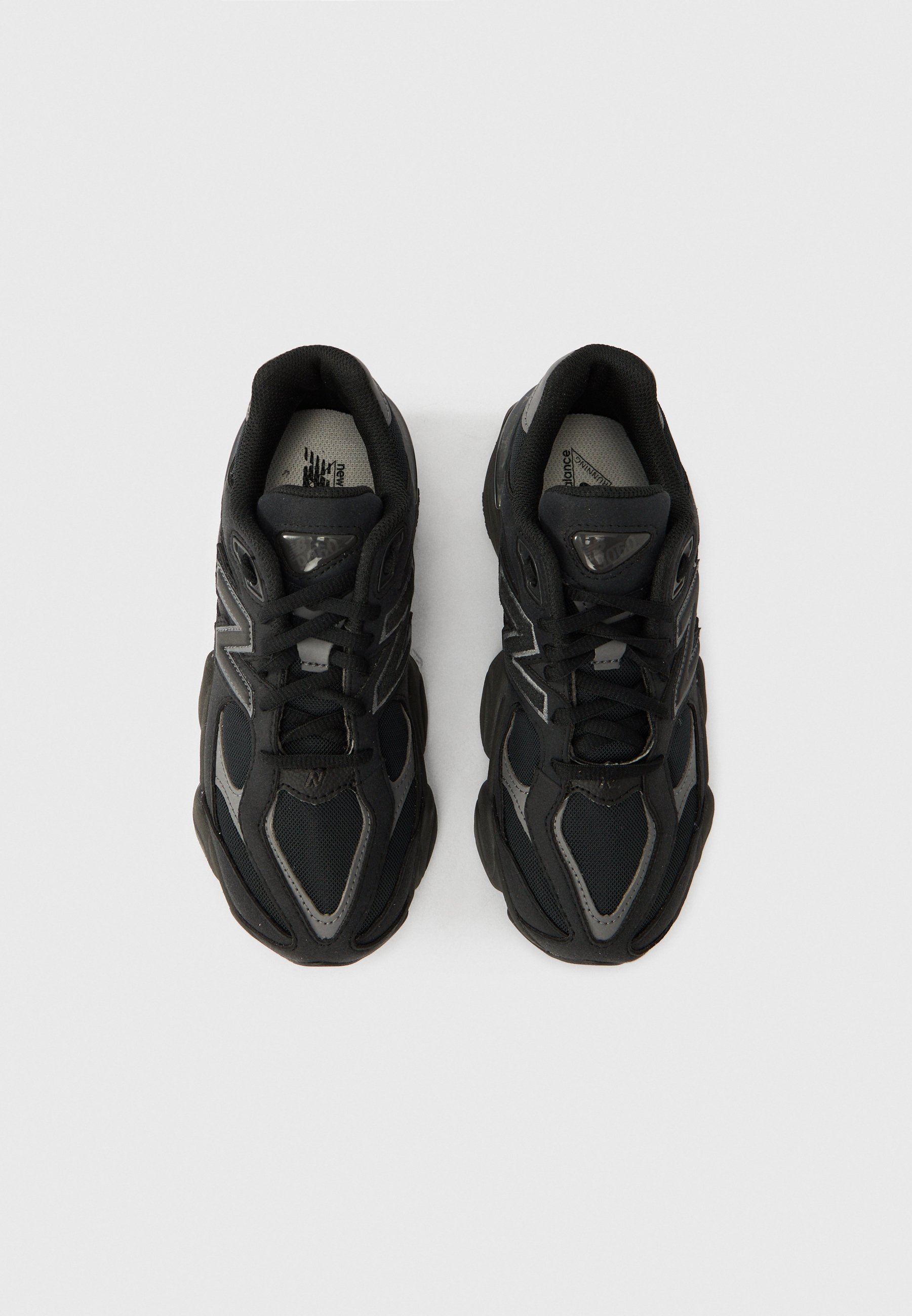 Zapatillas deportivas negras con parte superior de malla y sintético, puntera redondeada, suela gruesa de goma y detalles reflectantes en los laterales.