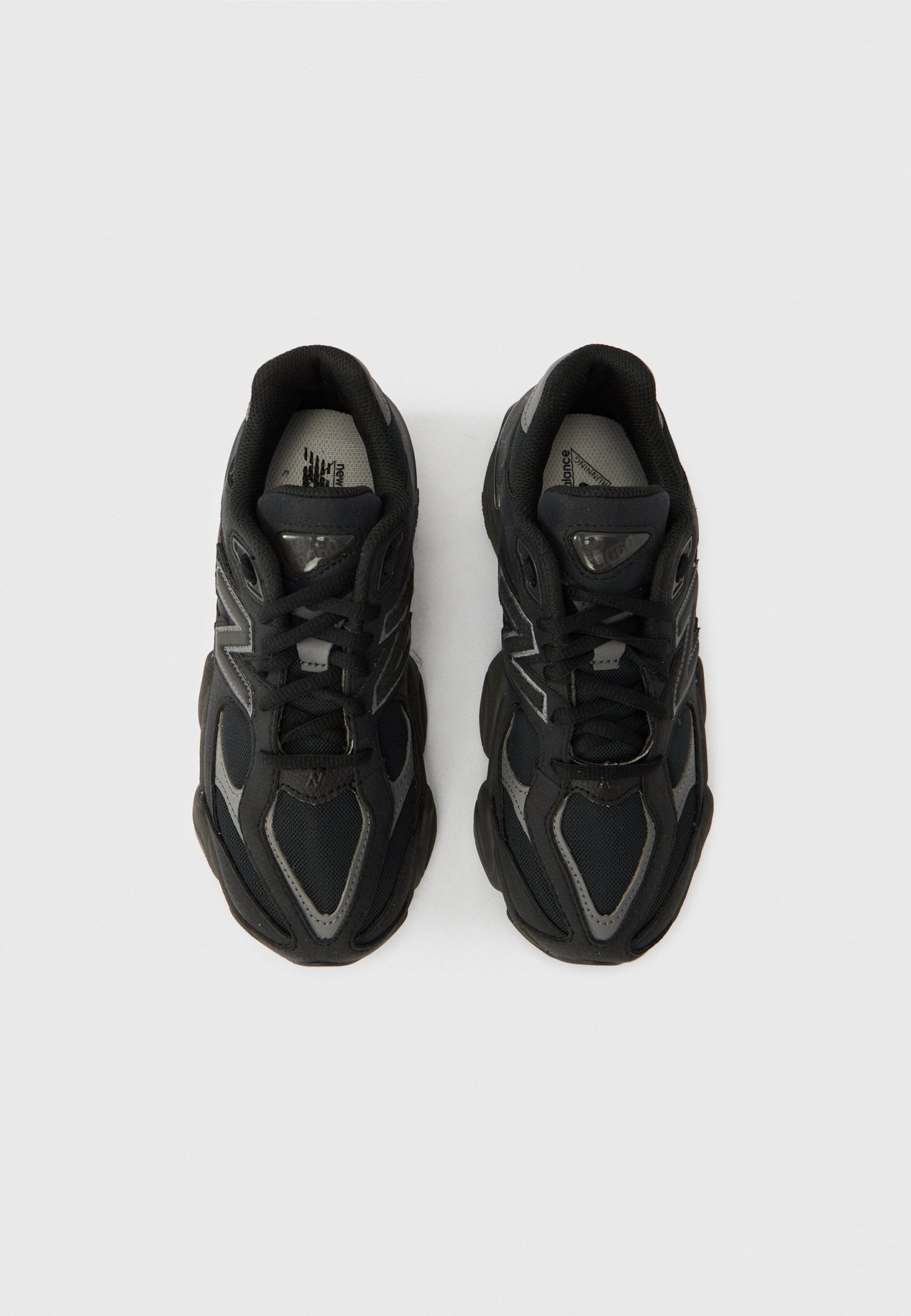 Zapatillas deportivas negras con parte superior de malla y sintético, puntera redondeada, suela gruesa de goma y detalles reflectantes en los laterales.