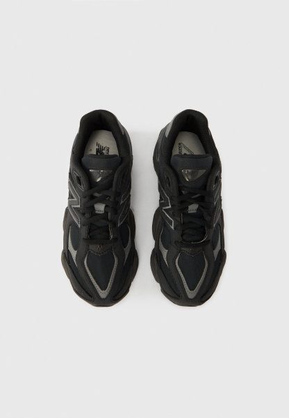 Zapatillas deportivas negras con parte superior de malla y sintético, puntera redondeada, suela gruesa de goma y detalles reflectantes en los laterales.