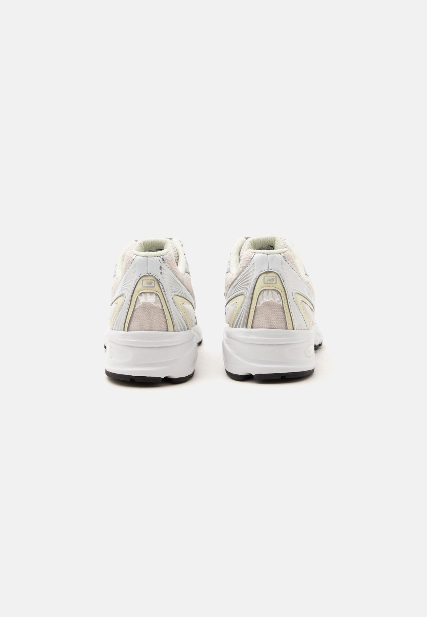 Par de zapatillas deportivas blancas con detalles beige vistas desde atrás sobre un fondo blanco liso.