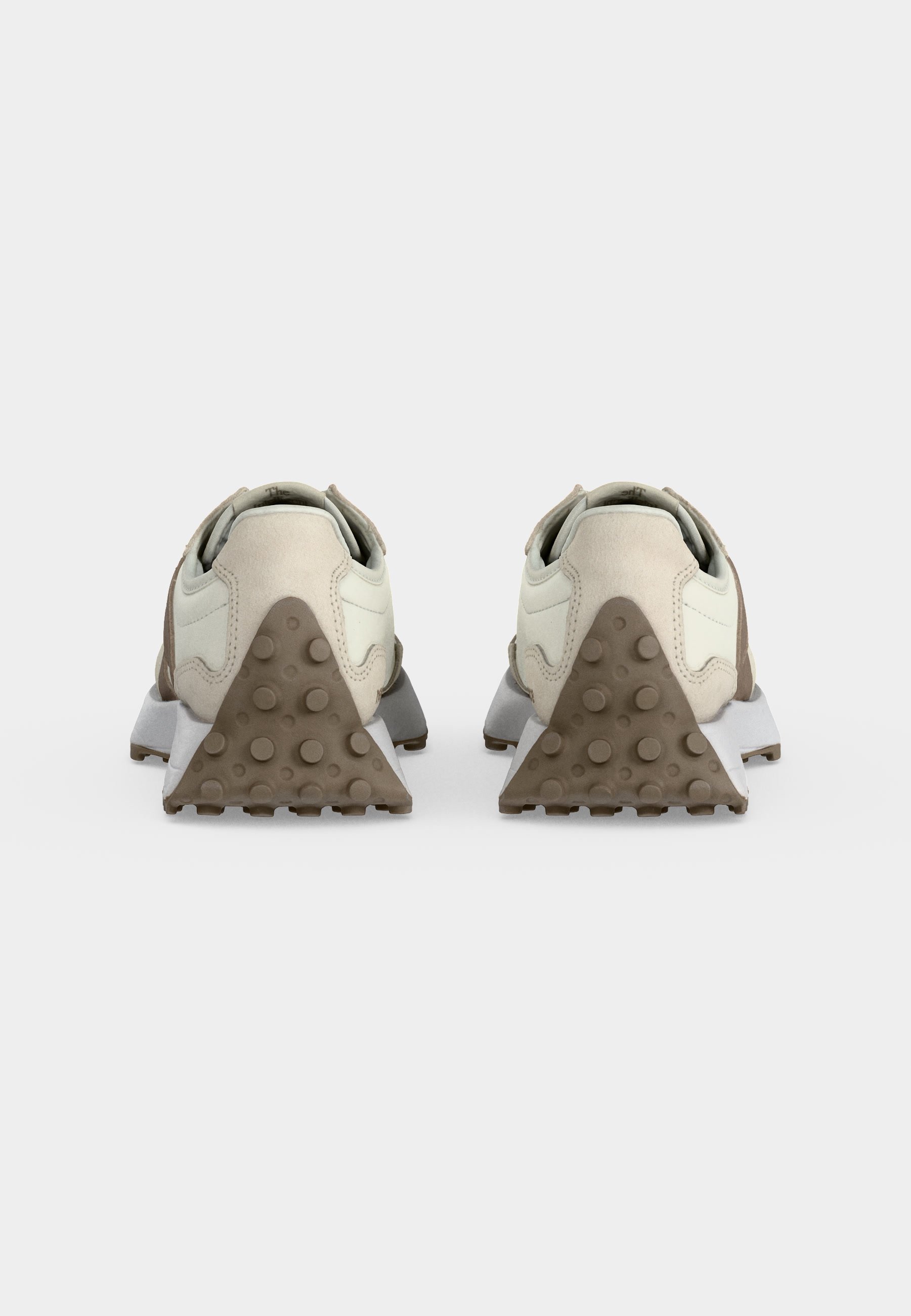Par de zapatillas beige y blancas vistas desde atrás, con cubiertas de goma texturizadas en el talón en forma triangular con agarres circulares.