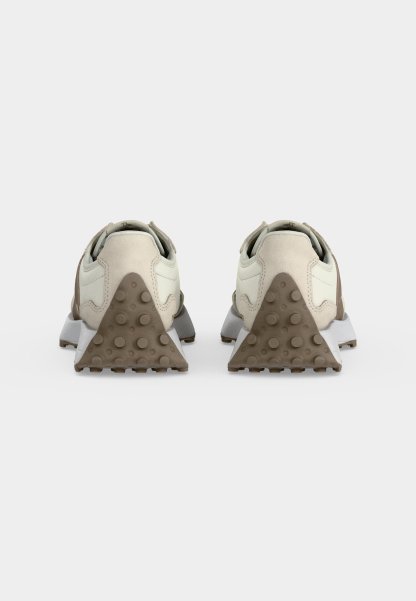 Par de zapatillas beige y blancas vistas desde atrás, con cubiertas de goma texturizadas en el talón en forma triangular con agarres circulares.