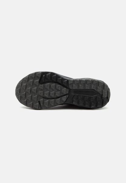 Suela de zapato de goma negra con profundas ranuras y bordes triangulares diseñados para tracción en diversas superficies.