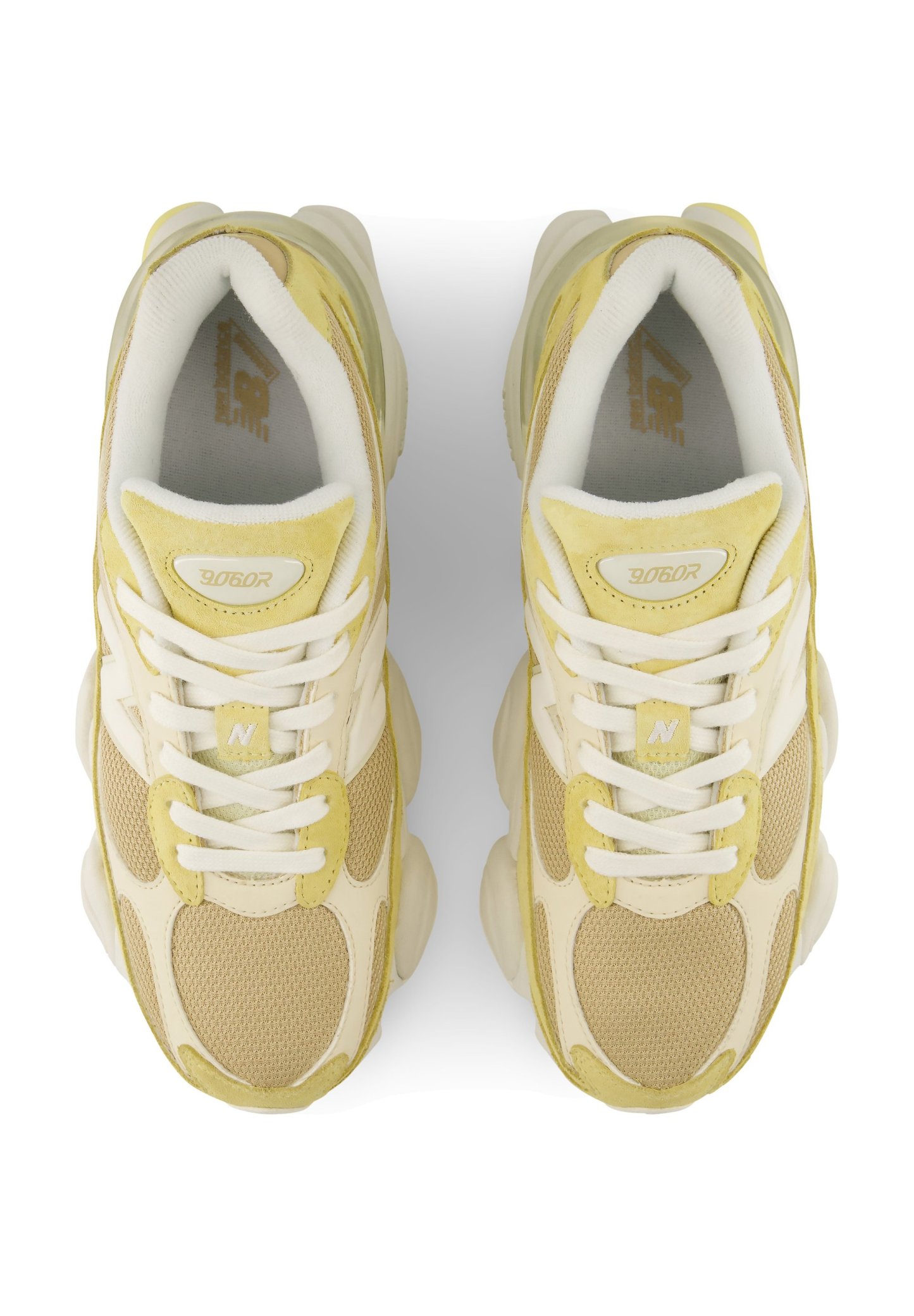 Par de zapatillas deportivas beige y amarillas con cordones blancos vistas desde arriba sobre un fondo blanco.