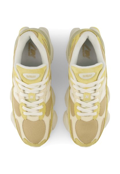 Par de zapatillas deportivas beige y amarillas con cordones blancos vistas desde arriba sobre un fondo blanco.