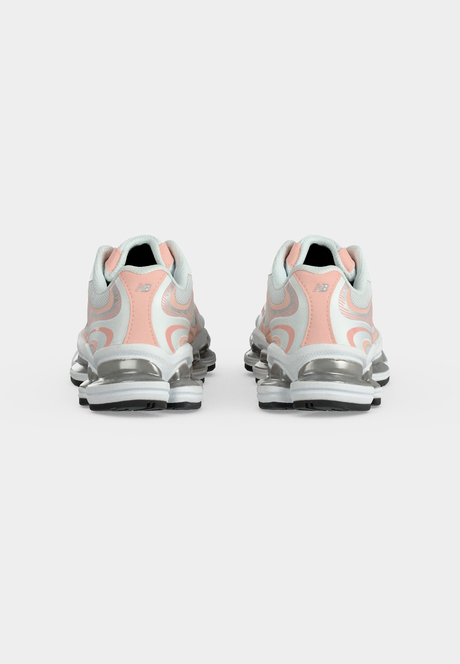 Zapatillas deportivas blancas y rosas con suelas acolchadas plateadas, mostradas desde atrás sobre un fondo blanco liso.