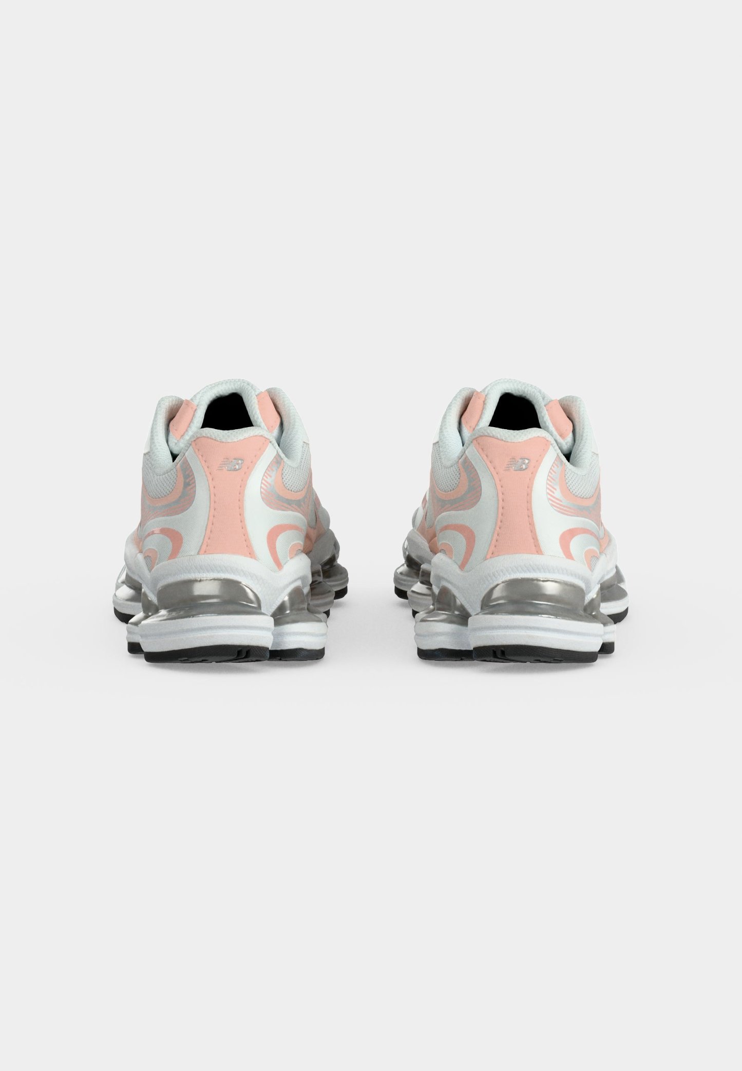 Zapatillas deportivas blancas y rosas con suelas acolchadas plateadas, mostradas desde atrás sobre un fondo blanco liso.