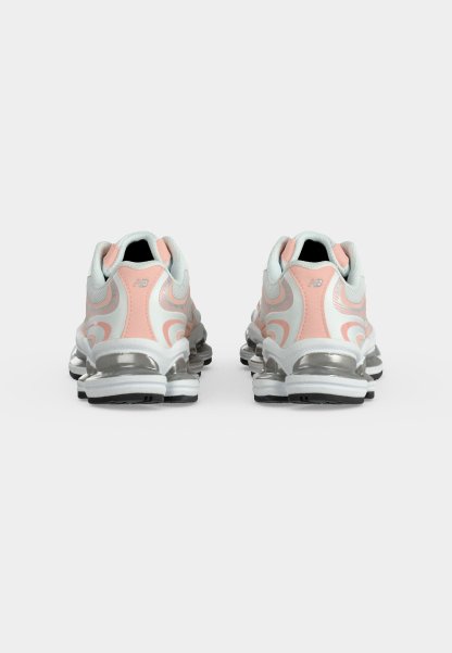 Zapatillas deportivas blancas y rosas con suelas acolchadas plateadas, mostradas desde atrás sobre un fondo blanco liso.
