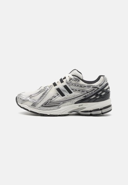 Zapatillas de running para hombre en malla blanca con acentos negros, que cuentan con una suela acolchada, diseño con cordones y una superficie texturizada para agarre.