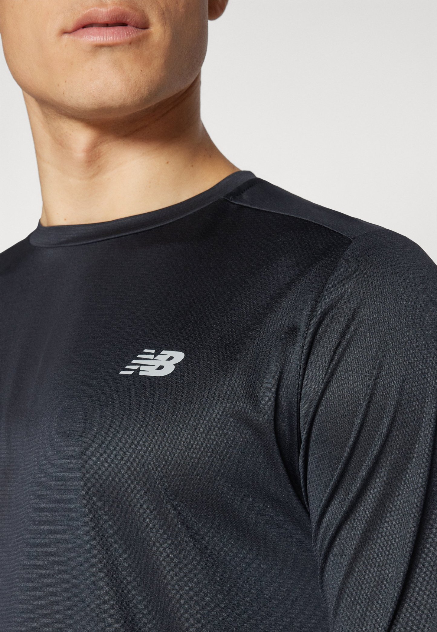 Camiseta atlética negra con un cuello redondo, hecha de una tela suave; presenta un pequeño logotipo blanco en el pecho.
