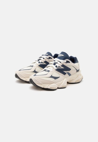 Par de zapatillas deportivas New Balance blancas y azul marino con suelas gruesas, cordones y detalles de tejido de malla sobre un fondo blanco.