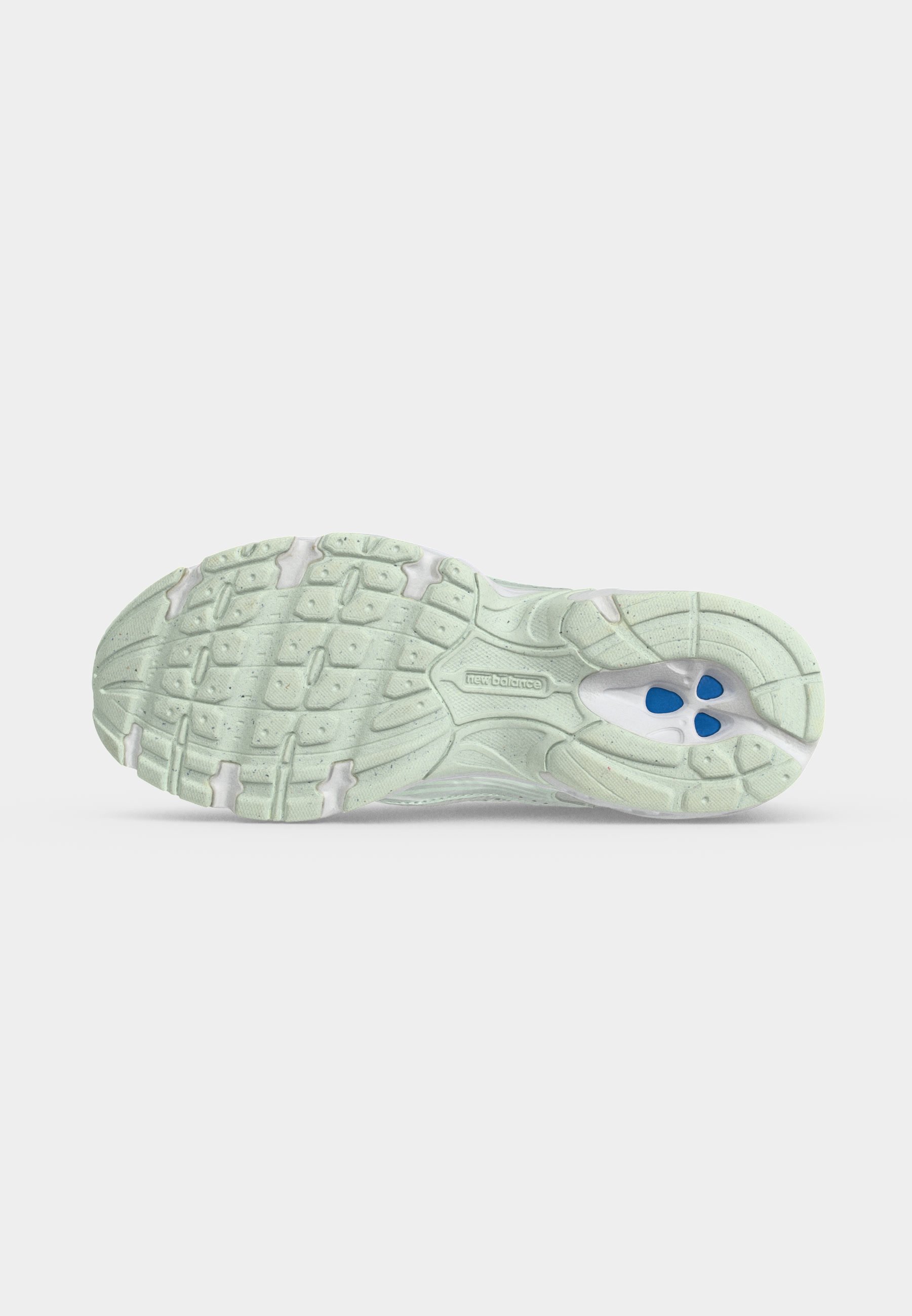 Suela de una zapatilla de correr New Balance de color verde claro que muestra el patrón de la banda de rodadura y elementos de amortiguación azul bajo el arco.