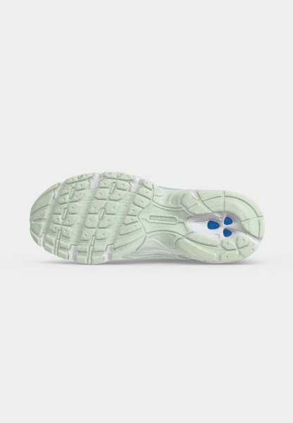 Suela de una zapatilla de correr New Balance de color verde claro que muestra el patrón de la banda de rodadura y elementos de amortiguación azul bajo el arco.