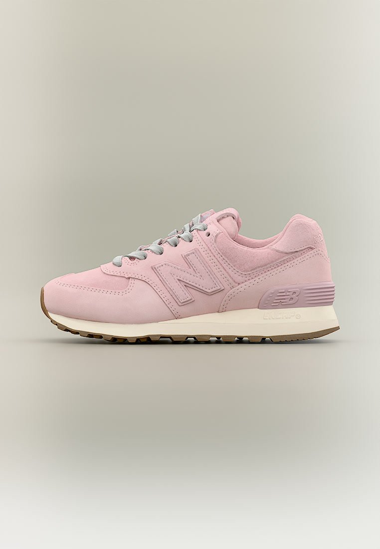 Zapatilla New Balance de color rosa claro con cordones grises, entresuela beige y suela exterior marrón, mostrada desde el lado exterior sobre un fondo neutro.